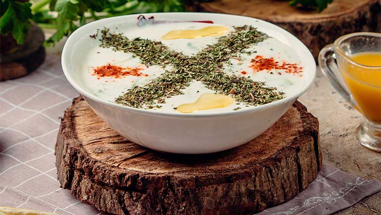 در دنیای پرمشغله امروز، همه ما به دنبال غذاهایی هستیم که هم ساده آماده شوند، هم سبک و مقوی باشند. خوشبختانه فرهنگ غذایی ایران سرشار ازاین‌دست خوراکی‌های خوشمزه است؛ غذاهایی که اغلب با مواد اولیه در دسترس درست می‌شوند و با طعمی اصیل، نظر هر فردی با هر سلیقه غذایی را جلب می‌کنند.

خوراک‌های نانی بخش مهمی از این غذاهای سبک و ساده را تشکیل می‌دهند. از دیرباز تا امروز، نان در کنار انواع خوراک‌های خانگی، همیشه جایی ویژه در سفره‌های ایرانی داشته است. غذاهایی مثل «نان و پنیر و سبزی»، «نان و املت»، «نان و کشک» یا حتی خوراک‌های نانی مخصوص شهرهای مختلف، بخشی از هویت غذایی ما را شکل داده‌اند. در ادامه 5 غذای نونی ایرانی را به شما معرفی و دستور پخت آن را ساده و سریع مرور می‌کنیم:

1.      کله‌جوش؛ غذای نونی فصل بهار

کله‌جوش یک غذای سبک و ساده ایرانی است که سرشار از پروتئین و کلسیم است. خوردن این خوراک را برای تقویت بدن در روزهای معتدل بهار توصیه می‌کنیم. آیا می‌دانید نام دیگر کله‌جوش چیست؟

مواد لازم:

·         کشک ساییده شده: ۱ پیمانه

·         پیاز: ۲ عدد

·         گردو خرد شده: ۳ قاشق غذاخوری

·         نعنا خشک: ۱ قاشق غذاخوری

·         نمک و فلفل: به میزان لازم

·         زردچوبه: کمی

·         روغن یا کره: ۲ قاشق غذاخوری

طرز تهیه کله‌جوش

پیازها را خلالی خرد و سرخ کنید تا طلایی شوند. زردچوبه و نعنا را اضافه کرده، کمی تفت دهید. کشک را رقیق کرده و به مواد اضافه کنید. گردوهای خرد شده را هم بیفزایید و اجازه دهید کمی بجوشد. کله‌جوش آماده است! کله‌جوش را بهتر است با نان سنگک تازه میل کنید تا طعم سنتی و اصیلش بیشتر احساس شود. این خوراک سبک و ساده را با نام کال‌جوش یا آش کشک هم می‌شناسند.

2.      دوپیازه آلو؛ یک خوراک فوری و مقوی

اگر به دنبال یک منبع خوب انرژی، فیبر و ویتامین C هستید، دوپیازه آلو برای وعده‌های فوری مناسب است. درست‌کردن دوپیازه آلو کمتر از نیم ساعت زمان می‌برد. آیا می‌دانید چرا با اینکه در این غذا آلو وجود ندارد، به آن دوپیازه آلو می‌گویند؟!

مواد لازم برای درست‌کردن دوپیازه آلو

·         سیب‌زمینی: ۳ عدد متوسط

·         پیاز: ۲ عدد

·         زردچوبه: کمی

·         نمک و فلفل: به میزان لازم

·         روغن: ۳ قاشق غذاخوری

طرز تهیه:

سیب‌زمینی‌ها را آب‌پز کرده و خرد کنید. پیازها را خلالی سرخ کنید تا طلایی شوند. سیب‌زمینی را اضافه کرده، با نمک، فلفل و زردچوبه تفت دهید. بهتر است دوپیازه آلو را با نان لواش گرم سرو کنید؛ سبکی نان، مکمل لطافت خوراک است. این غذا، خوراک محلی شیراز است. در شیراز و بوشهر به سیب‌زمینی، آلو زمینی می‌گویند. به همین دلیل است که نام این خوراک دوپیازه آلوست.

3.      میرزاقاسمی؛ مخصوص علاقه‌مندان بادمجان!

میرزاقاسمی غذایی سبک، پر از فیبر و آنتی‌اکسیدان است و برای افرادی که به دنبال  رژیم‌های سالم هستند توصیه می‌شود. میرزاقاسمی با نان تافتون داغ یک ترکیب بی‌نظیر و خوشمزه می‌شود.

مواد لازم:

·         بادمجان: ۳ عدد بزرگ

·         تخم‌مرغ: ۲ عدد

·         گوجه‌فرنگی: ۲ عدد

·         سیر: ۴ حبه

·         نمک و فلفل: به میزان لازم

·         روغن: ۳ قاشق غذاخوری

طرز تهیه:

بادمجان‌ها را کباب کرده و پوست بگیرید. له کنید و با سیر خرد شده تفت دهید. گوجه‌ها را خردکرده اضافه کنید. وقتی آب گوجه کشیده شد، تخم‌مرغ‌ها را افزوده و هم بزنید تا پخته شود.

4.      آبگوشت؛ غذای نونی ظهرهای جمعه

آبگوشت منبع فوق‌العادهٔ پروتئین، فیبر و انرژی است که اکثر ما ایرانی‌ها این غذاها را به‌صورت دسته‌جمعی و با نان‌های تریدی مصرف می‌کنیم. پیشنهاد می‌کنیم آبگوشت را حتماً با نان سنگک برشته یا با نان سنتی یزد نوش جان کنید.

مواد لازم برای درست‌کردن آبگوشت

·         گوشت گوسفندی: ۳۰۰ گرم

·         نخود و لوبیاسفید: ۱ پیمانه

·         سیب‌زمینی: ۲ عدد

·         گوجه‌فرنگی: ۲ عدد

·         پیاز: ۱ عدد

·         رب گوجه: ۱ قاشق غذاخوری

·         نمک، فلفل، زردچوبه: به میزان لازم

طرز تهیه:

حبوبات را از شب قبل خیس کنید. گوشت، پیاز و حبوبات را با ادویه‌ها بپزید. سیب‌زمینی و گوجه‌ها را بعد از 20 دقیقه اضافه کنید. پس از پخت (حدود 4 تا 5 ساعت)، مقداری رب تفت داده و به آبگوشت اضافه کنید. اجازه دهید تا حسابی جا بیفتد، سپس میل کنید.

5.      کوکوسبزی؛ غذای نونی ایرانی برای گیاه‌خواران

اگر گیاه‌خوار هستید یا غذاهایی مثل آبگوشت به دلیل چربی زیاد را نمی‌پسندید، یک انتخاب بهتر برای شما داریم: کوکوسبزی. این خوراک ساده و سبک سرشار از ویتامین‌ها و مواد معدنی است و به دلیل اینکه کالری کمی دارد برای وعده‌های سبک مثل شام یا عصرانه مناسب است.

مواد لازم:

·         سبزی کوکو (تره، جعفری، گشنیز، شوید): ۳ پیمانه خرد شده

·         تخم‌مرغ: ۴ عدد

·         گردو خرد شده: ۲ قاشق غذاخوری (اختیاری)

·         نمک و فلفل: به میزان لازم

·         زردچوبه: کمی

·         روغن: ۳ قاشق غذاخوری

طرز تهیه کوکوسبزی

سبزی‌ها را با تخم‌مرغ و ادویه‌ها مخلوط کنید. در ماهیتابه روغن بریزید، مایه را اضافه کنید و هر دو طرف را سرخ کنید تا طلایی شود. اگر می‌خواهید طعمی جدید و متفاوت به کوکوسبزی بدهید، کمی زرشک، پیازداغ و گردو خرد شده به مخلوط سبزی اضافه کنید. بهترین نان برای خوردن کوکوسبزی، نان بربری تازه یا تست شده است.

اگر شما هم به دنبال ایده‌هایی خوشمزه و آسان برای یک وعدهٔ ساده و دلپذیر شام یا عصرانه هستید، پیشنهاد می‌کنیم سری به مجله زیوامگ بزنید. در این مجله، علاوه‌بر دستورپخت خوراک‌های خاطره‌انگیز ایرانی، رژیم‌های غذایی مناسب، انواع سالاد رژیمی و لیست غذاهای ایرانی هم آشنا می‌شوید. زیوامگ با ارائه پیشنهاد فعالیت بدنی و ورزش، شما را برای سوزاندن انرژی حاصل از این غذاهای نانی راهنمایی می‌کند.

جمع‌بندی

در میان انواع غذاهای سفره ایرانی، غذاهای نانی نه‌تنها سبک و ساده‌اند، بلکه برای وعده‌هایی مثل صبحانه، عصرانه یا شام‌های سبک ایدئال هستند. تجربهٔ این خوراک‌ها شما را به دل سنت‌های خوشمزه ایرانی خواهد برد و طعم زندگی ساده و صمیمی را به شما یادآوری می‌کند.